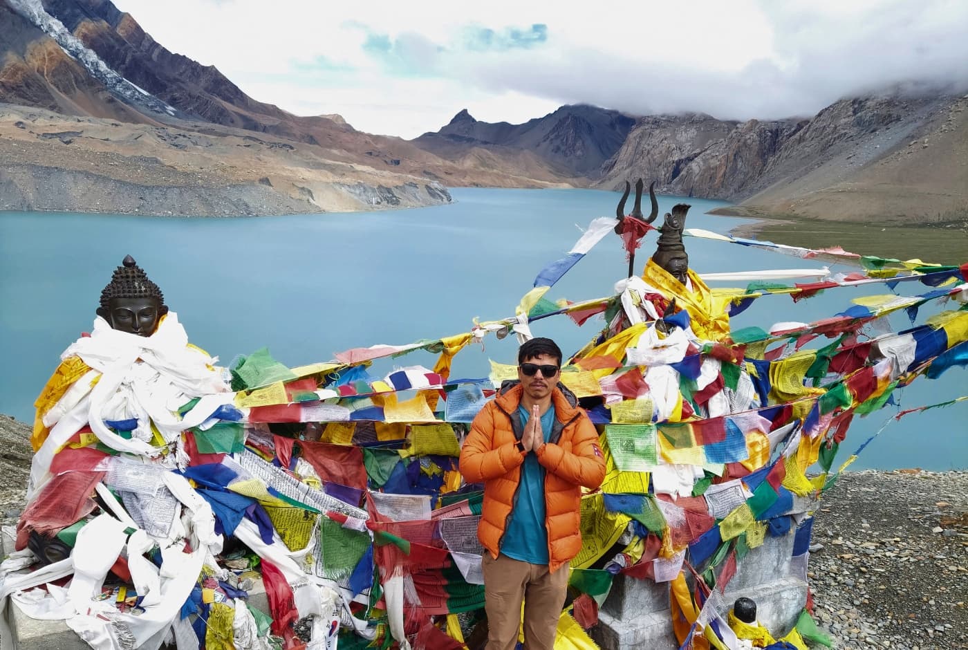 Traveler at Tilicho Lake, surrounded by prayer flags and stunning mountain views