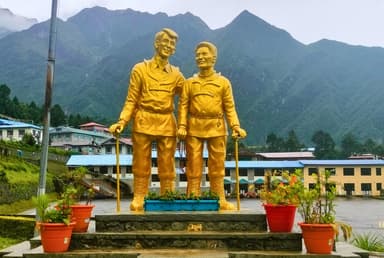 Golden statue of Sir Edmund Hillary and Tenzing Norgay at Lukla, Nepal, with mountains