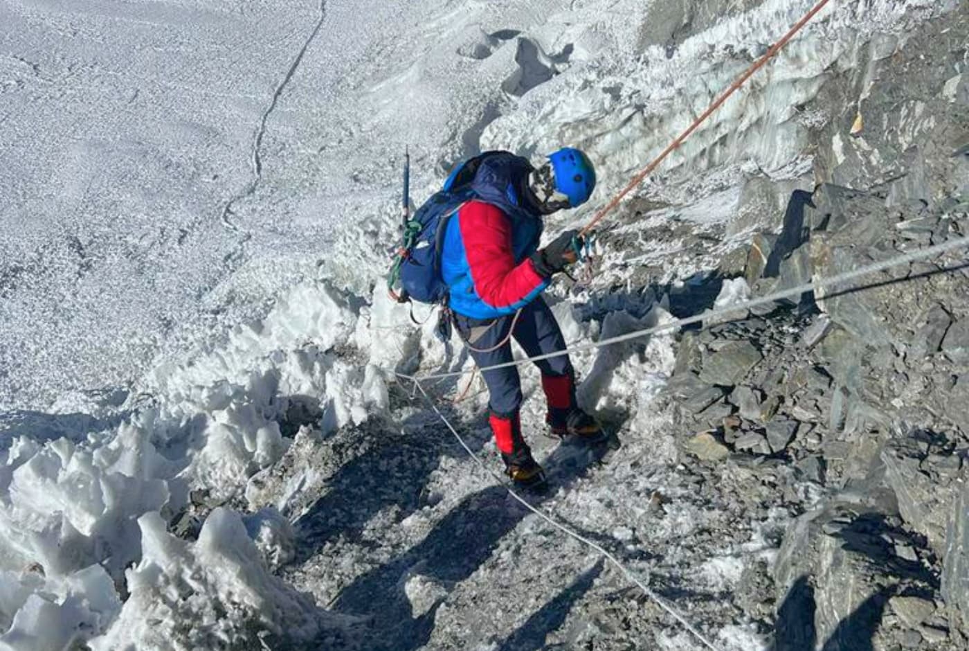 Climber descending a snowy and rocky slope using ropes on a mountain