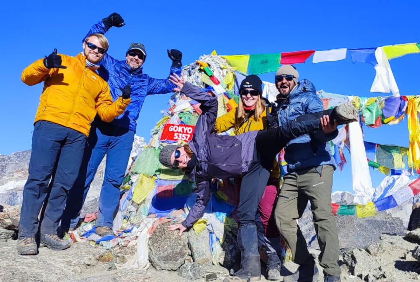 Group of hikers celebrating at Gokyo Ri summit with prayer flags