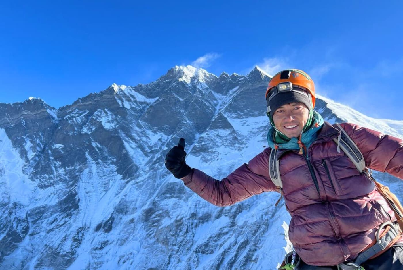 Smiling climber giving a thumbs up with snow Covered mountain   Island Peak