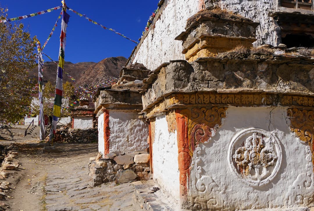 Ancient Lo Gekar Gompa With Tibetan Buddhist Stupa, Carved Murals, And Colorful Prayer Flags