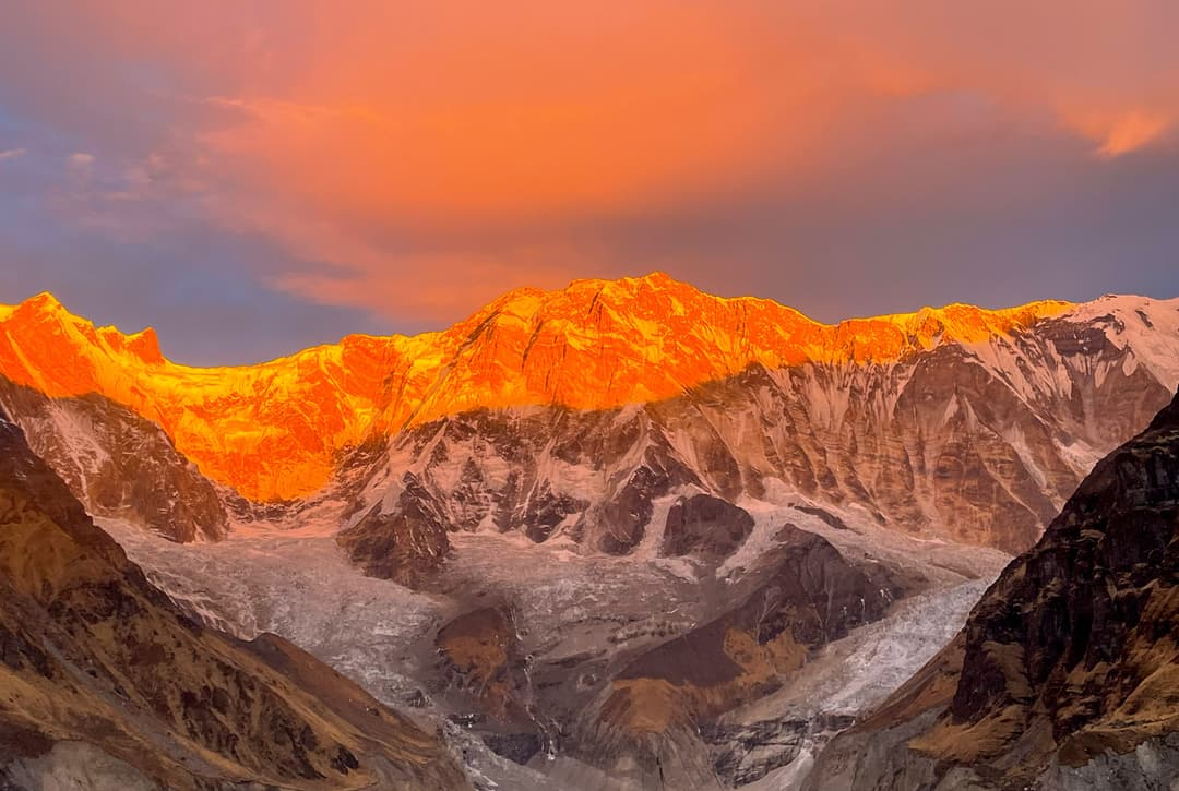 Sunrise alpenglow on Annapurna peaks viewed from Base Camp at dawn before descent