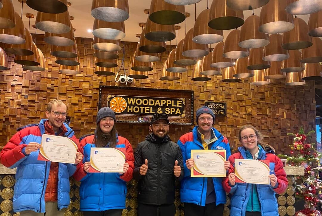 Group of trekkers holding Everest Base Camp trek completion certificates at a hotel in Kathmandu.