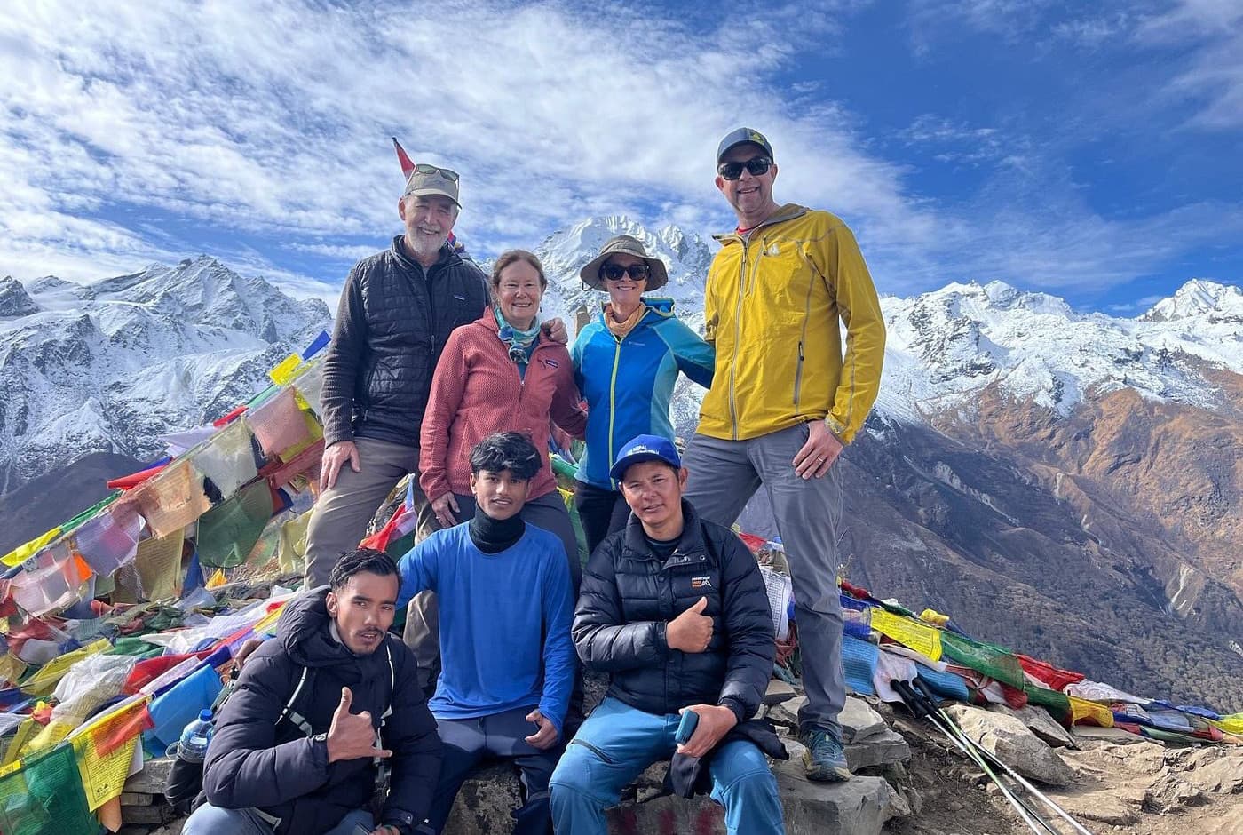 Trekkers and Nepal Hiking Team crew at Kyanjin Ri viewpoint during Langtang Valley Trek with snowy Himalayan peaks in the background.